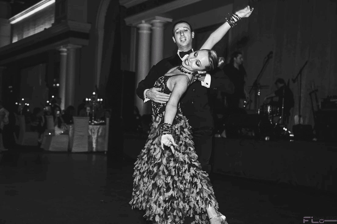Black-and-white shot of a ballroom dance couple mid-spin, band on stage behind