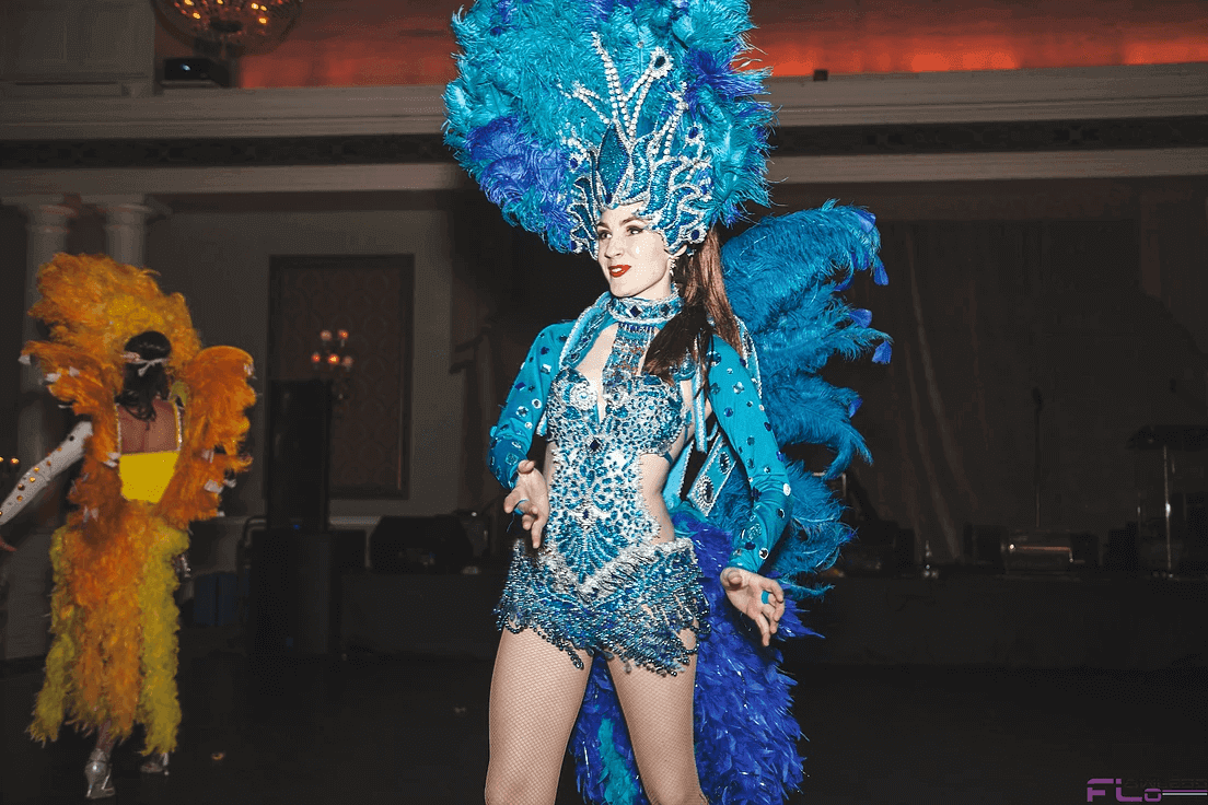 Samba dancer in a blue feathered headdress and sequined costume on the dance floor