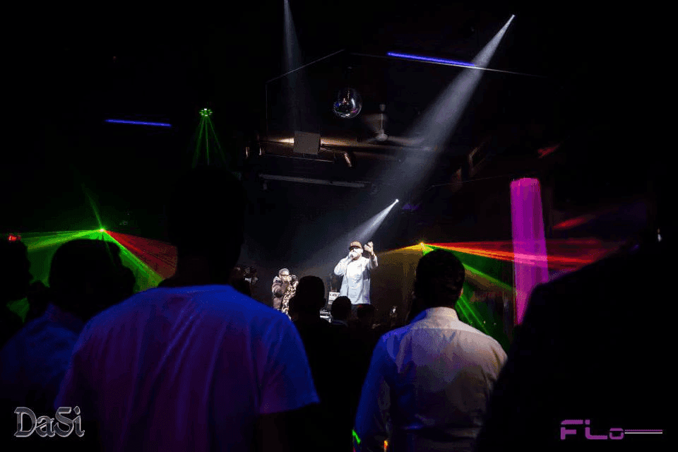 MCs on stage framed by green and red lasers, mirror ball and moving-head beams