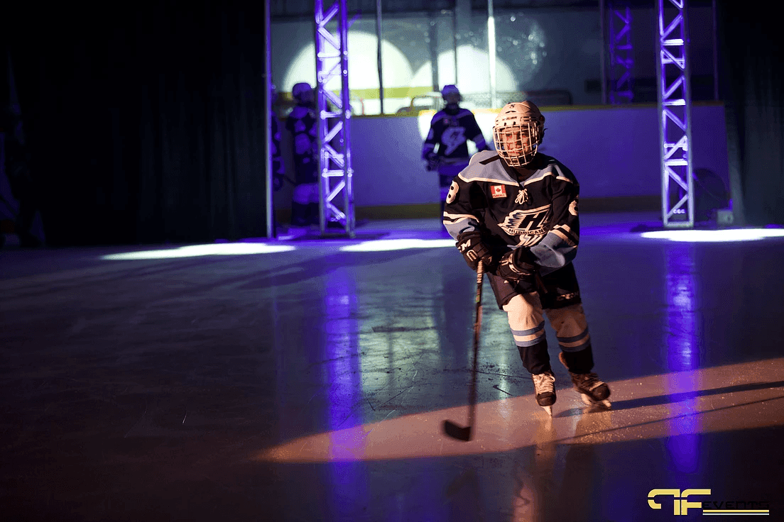 Young player skates through the lit truss arch into a spotlight during introductions