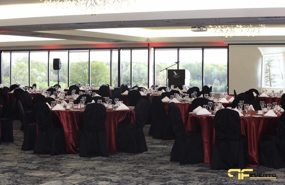 Dinner room set with red linens, podium and red uplighting along the windows
