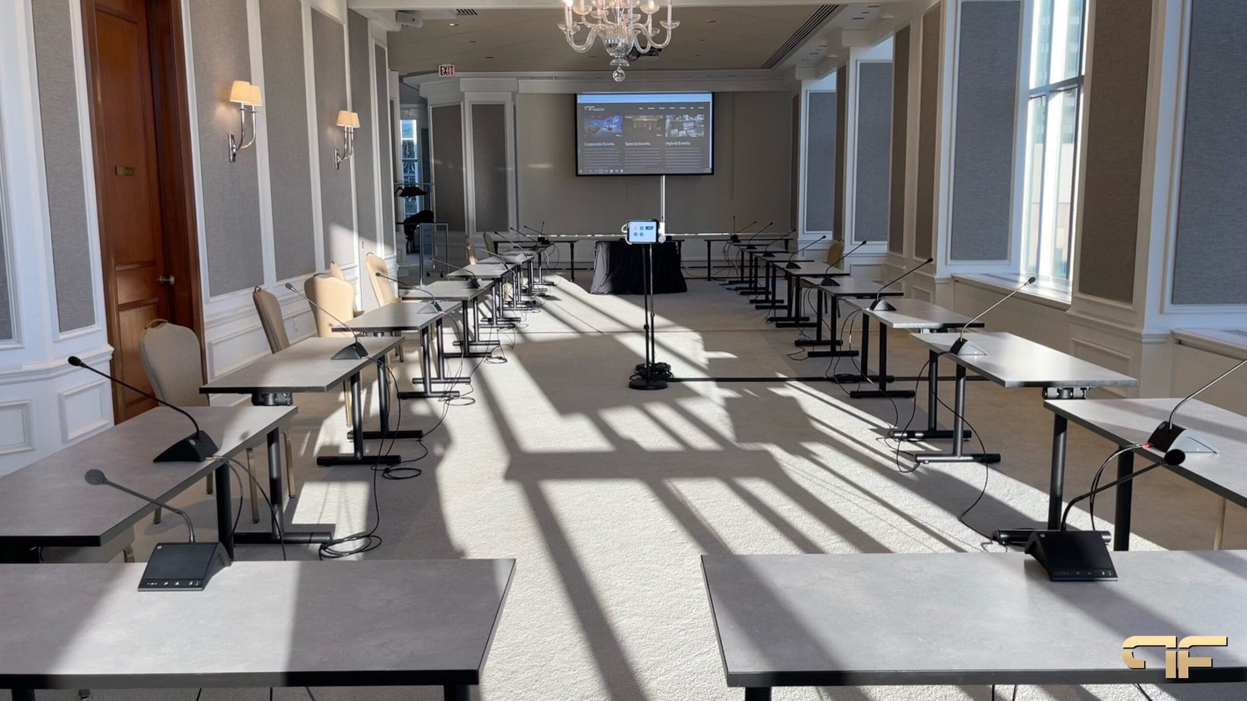 Conference room with rows of tables, gooseneck delegate mics and a projection screen
