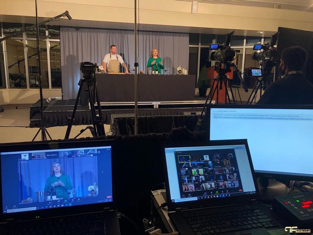 Livestreamed cooking demo on stage with cameras and Zoom monitors in front