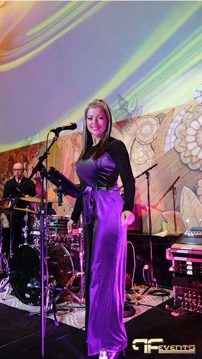 Singer in purple on stage under a swirling multicolour projection