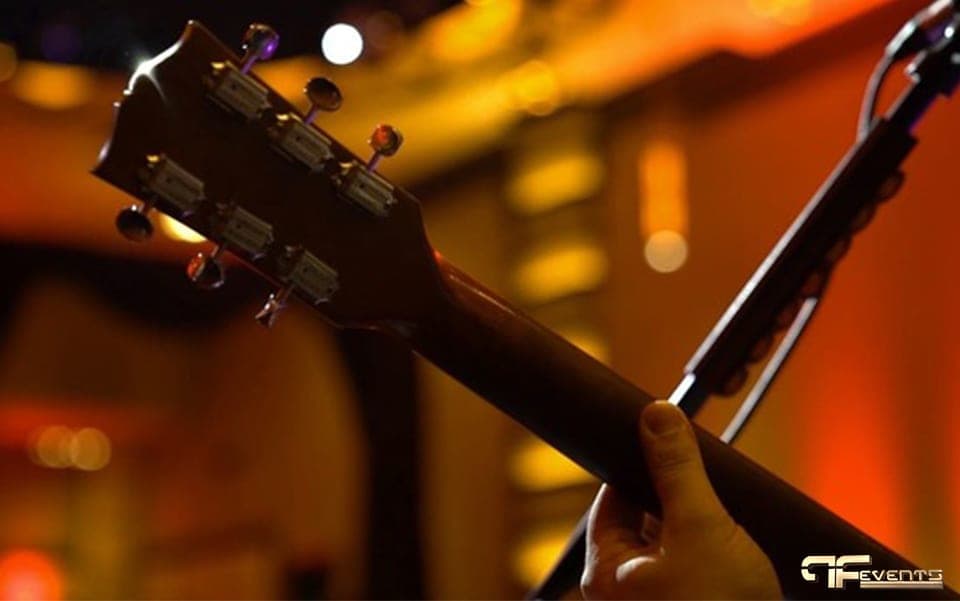 Close-up of a guitar headstock against warm amber stage lights