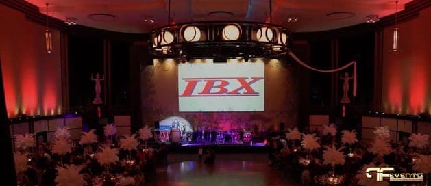 Eglinton Grand ballroom with white feather centrepieces, red uplight and IBX logo