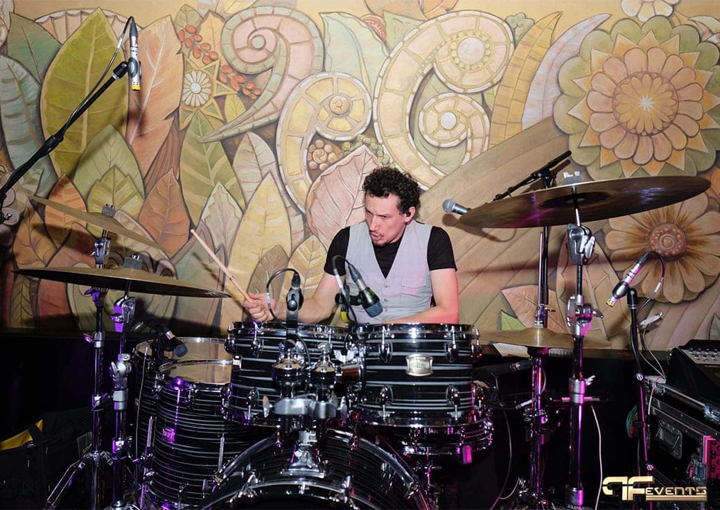 Drummer on a fully miked kit in front of the Eglinton Grand floral mural